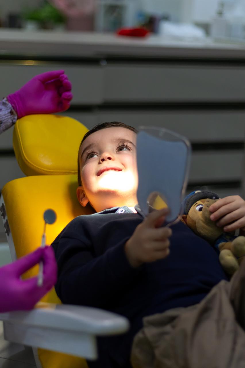 Criança feliz na cadeira odontológica